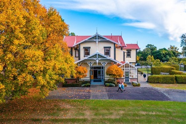 image shows people walking into a historical homestead in autumn